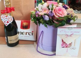 Flower arrangement in a hat box with sweets and champagne